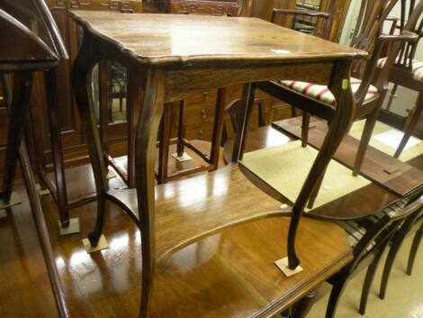 An Edwardian oak two tier table on shaped supports