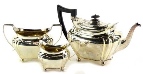 An Edwardian silver three piece tea set, the teapot with an ebonised knop and handle, of melon shape, on ball feet, Sheffield 1909, 31½ oz all in.