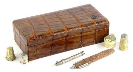 An early 20thC case in crocodile skin finish decoration, 19cm wide, various thimbles, etc. (a quantity).