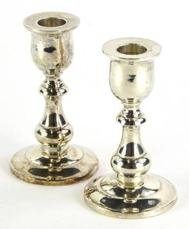 A pair of white metal squat candlesticks, each with urn dish holders, inverted baluster stems and domed circular feet, marked Thailand Sterling 925, 13cm high, 19oz all in (2, weighted).