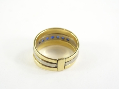 A three ring design single dress ring, with central platinum band, set with sapphires, with two outer coloured yellow metal bands, unmarked, ring size R, 8.4g all in. - 2