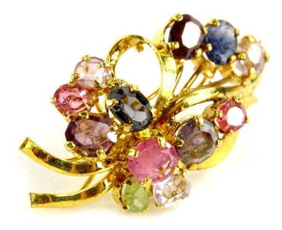 A costume jewellery brooch, set in the form of a floral spray, with multi coloured pink and purple stones, on a gold plated surround, 4cm long overall.