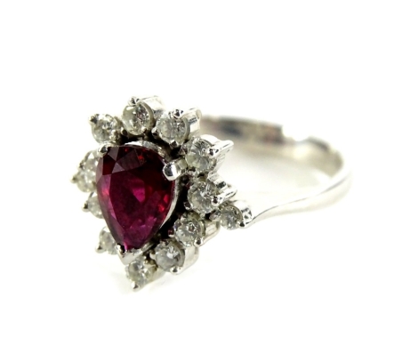 An 18ct white gold floral cluster ring, set with tier drop design, central ruby, surrounded by round brilliant cut tiny diamonds, the ruby 6.2mm x 7.9mm x 3.6mm, ring size R, 6.8g all in (boxed)