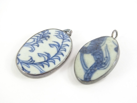 Two delft set and silver framed pendants, the first with white porcelain and blue fernspray design panel, in silver frame, 3.5cm wide, 4.5cm high, stamped to border Thailand, and another slightly curved design picturing part of a dragon, 4.5cm x 3cm, silv