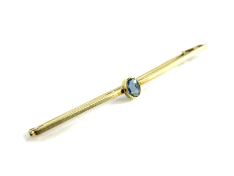 An aquamarine set bar brooch, with single oval aquamarine in rubover setting, on a yellow metal pin back, unmarked 6.5 cm wide, 2.6g all in.