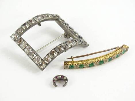 Three pieces of Victorian and later jewellery, comprising horseshoe silver framed stick pin top (AF) set with rubies and diamonds, a paste stone set curved bar brooch, with green and white paste stone set, silver buckle converted to a brooch (3).