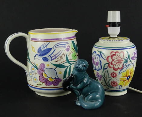 Three items of Poole pottery, a large jug decorated with flowers, birds in typical manner, printed mark in grey to underside, a similar lamp base and a model of an otter with a fish.