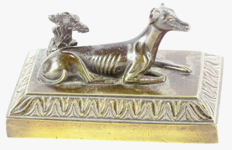 A 19thC bronze model of a reclining hound beside grape vine, on a rectangular base, 13cm wide.