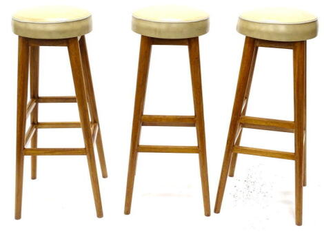 A set of three eastern hardwood bar stools, each with cream leatherette padded seat 82cm high. The upholstery in this lot does not comply with the 1988 (Fire & Fire Furnishing) Regulations, unless sold to a known exporter or upholsterer it will be cut fr