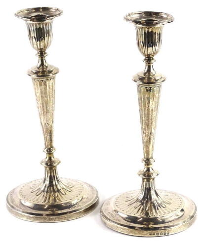 A pair of early Victorian silver candlesticks, each with a reeded sconce, fluted tapering column and a circular base cast with a flower head, initialled JAG to base, loaded, Sheffield 1837 by John Parsons and Co., 29cm high. Provenance: The Estate of Mis