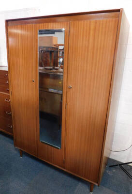 A Nathan teak double wardrobe, with a central mirrored section flanked by two doors, raised on cylindrical legs and brass capped feet, 176.5cm high, 122cm wide, 58cm deep.