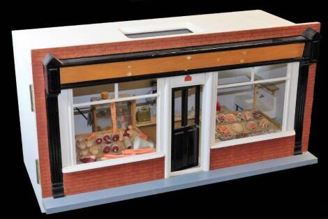 A 20thC model butcher's shop, the articulated front numbered 50, with realistic meat, some pieces removable, opening to reveal till, butcher and various implements, cleavers, etc., predominately decorated in white with grey and black highlights, 30cm high