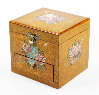 A painted vanity box, decorated with gilt coloured scrolls, the lid heavily decorated with flowers hinging to reveal an articulated mirror of rectangular form with sectional interior and front drawer, 19cm high, 20cm wide, 19cm deep.