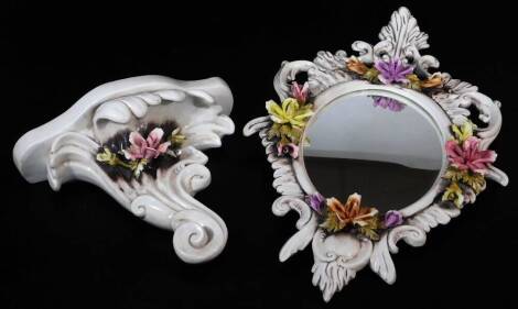 A 1970's Capodimonte mirror, of oval form, elaborately decorated and raised with flowers with a sconce scroll shelf, 32cm high. (2)