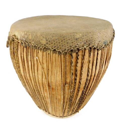 A 20thC African tribal drum, of shaped form, with strung centre on circular foot, 55cm high.