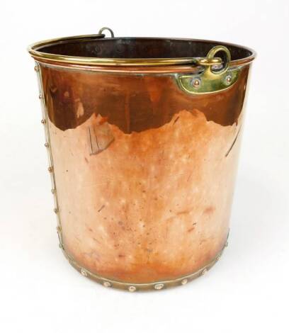 An early 20thC copper coal bucket, of cylindrical studded form with swing brass handle, the main body 30cm high.