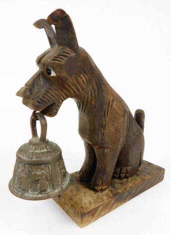 A 20thC carved treen figure, of a dog holding metal bell to the mouth, on plain rectangular base, 21cm high.