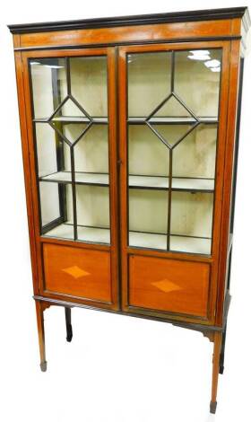 An Edwardian mahogany display cabinet, with an inlaid bell flower and bow frieze above two astragal glazed doors and diamond inlaid panels on square legs terminating in spade feet, 169cm high, 96cm wide, 34cm deep.