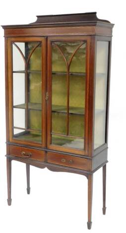 An Edwardian mahogany and boxwood strung display cabinet, with fixed cornice raised above two astragal glazed doors, flanked by plain glazed side panels revealing plain material lined shelves, on square tapering legs terminating in spade feet, 180cm high,