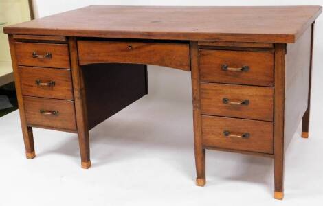 An Edwardian mahogany pedestal desk, the plain rectangular top raised above a central frieze drawer and two pedestals each set with three drawers on block stiles, terminating in compressed square feet, 79cm high, 156cm wide, 87cm deep.