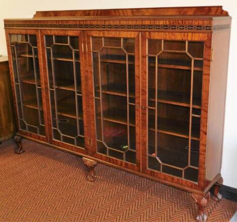 A mahogany bookcase of large proportion, the rectangular body set with a blind fret, above four astragal glazed doors, on squat shell capped claw and ball feet, 128cm high, 179cm wide, 32cm deep.