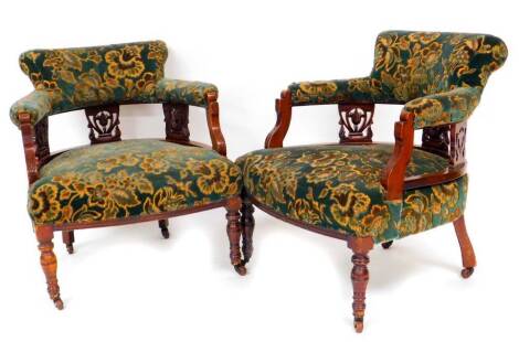 A pair of late 19thC low back chairs, each of C shape with overstuffed backs, arms and seats in elaborate floral pattern on turned front legs terminating in castors, 70cm high. (2)