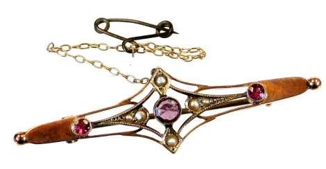 An Edwardian brooch, of shaped form with a triangular centre set with seed pearls, and three amethyst coloured stones with a plain pin back, marked 9c, 5cm wide, 2.3g all in.