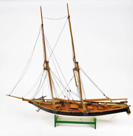 A 20thC wooden model of a warship, with realistic decking set with cannons and masts, on plain wooden base, 63cm high.