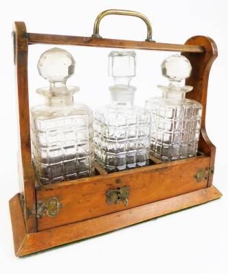 An Edwardian oak tantalus, with three decanters, on a plain base with metal mounts and key, 34cm high. (AF)