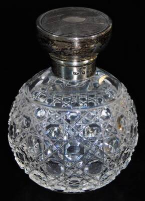 An early 20thC cut glass perfume bottle, with engine turned silver lid, 10cm high.