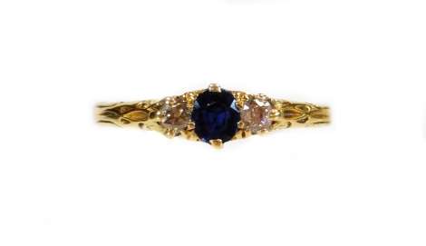 A 18ct gold dress ring, claw set with a central blue stone flanked by small diamonds, on a textured shank, size S, 2.2g all in.