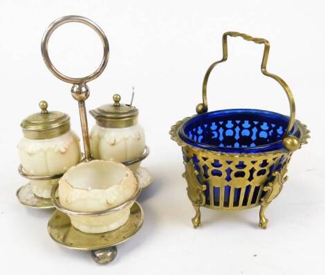 A base metal preserve pot, with blue glass liner and swing handle, 11cm wide, and a three piece cruet set, on plated stand. (2)