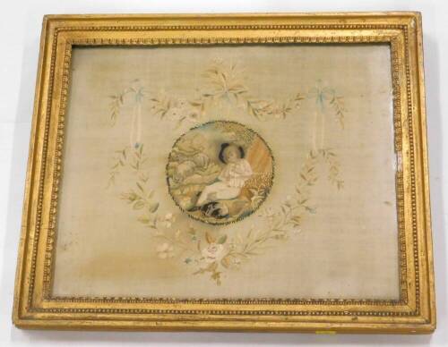 An early 19thC silk embroidered picture, decorated centrally with a young boy, sheep, etc., surrounded by a floral cartouche, embellished with ribbons, wheat ears, etc., 34.5cm x 42cm.