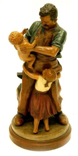 Joseph Kowarzik. (German 1860-1911), a painted terracotta figure of a blacksmith standing with a young girl and a baby, on a circular base, signed to base, 67cm high.