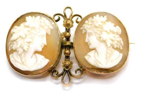 A late 19thC double cameo brooch, with two oval cameos of ladies facing each other, 22mm x 18mm, each frame in yellow metal rub over setting, with a column between two 2mm beads, each set near the floral decoration with decorative ends, yellow metal, stam