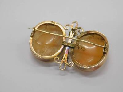 A late 19thC double cameo brooch, with two oval cameos of ladies facing each other, 22mm x 18mm, each frame in yellow metal rub over setting, with a column between two 2mm beads, each set near the floral decoration with decorative ends, yellow metal, stam - 2