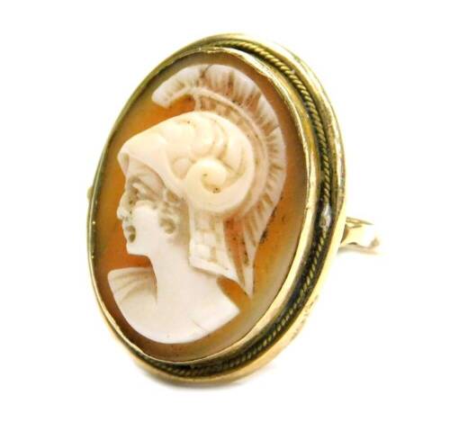 A 19thC shell cameo dress ring, the oval shell cameo with figure of a warrior in headdress, in a rub over yellow metal border, with scroll design ring frame, yellow metal, unmarked, ring size J, 4.4g all in.