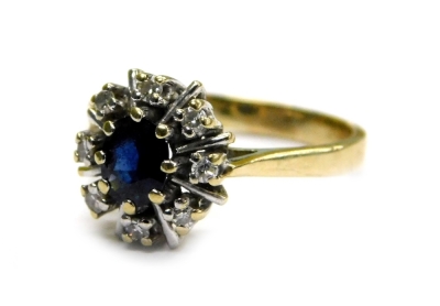 A 9ct gold cluster ring, set with central oval cut sapphire in gold eight claw setting, surrounded by tiny diamonds, broken by single platinum lines, ring size O, 3g all in.