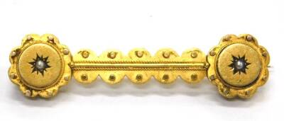 A Victorian bar brooch, with reeded and dot design, set with a single seed pearl at each end, yellow metal, unmarked, 5cm wide, 5.5g all in.