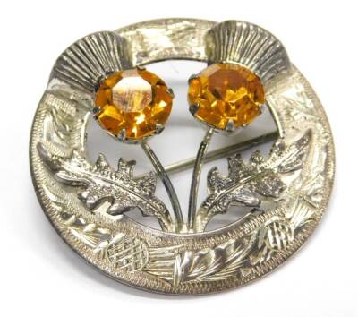 A silver plated thistle brooch, set with two orange coloured costume stones, 4cm wide.