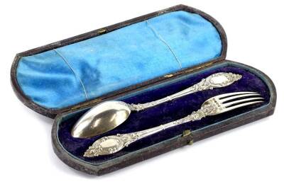 A Victorian silver christening set, comprising spoon and fork, each with a rococo scroll handle and vacant cartouche, London 1877, 1¾oz, in original fitted case. Provenance: The Estate of Miss Rachel Monson.