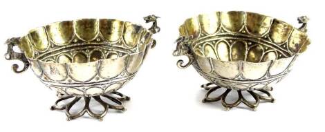 A pair of continental white metal salts, each with a gilt interior, cast as a flowerhead, etc., stylised 'C' line handles on a pierced petallated base, unmarked, 2oz. Provenance: The Estate of Miss Rachel Monson.