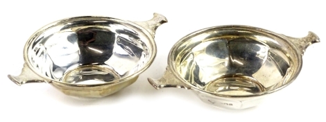 A pair of Edwardian silver two handled wine tasters, each a faceted form, Birmingham 1909, 2½oz.