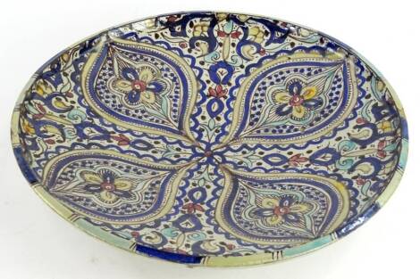 An Isnik pottery charger, decorated with four ovals in a quatrefoil design embellished with flowers, leaves, etc., 38cm diameter.