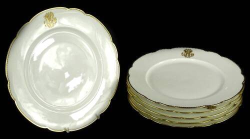 A set of six Limoges plates, each decorated in gilt with a monogram, within a shaped border, 25.5cm diameter.