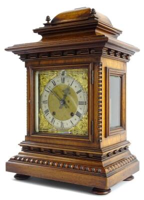 A late 19th/early 20thC German walnut mantel clock, the case decorated with beading reel, applied with turned brass finials, the square dial with gilt spandrels, with an eight day movement, 44cm high.