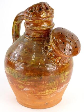 A rustic pottery watering can, with brown, green and black glazes, 37cm high.