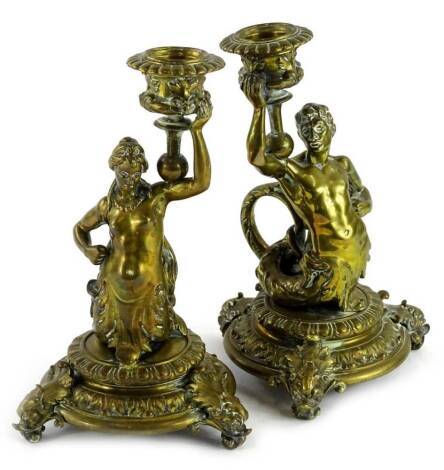 A pair of late 19thC continental gilt brass candlesticks, each modelled in the form of a male and female caryatid with shaped handle, circular foot and dolphin cast feet, worn, 19cm high.