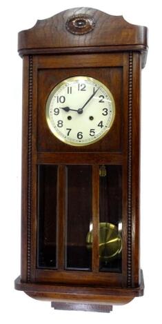 A 1920s oak wall clock, the dial with Arabic numerals, flanked by beaded sides, 77cm high.