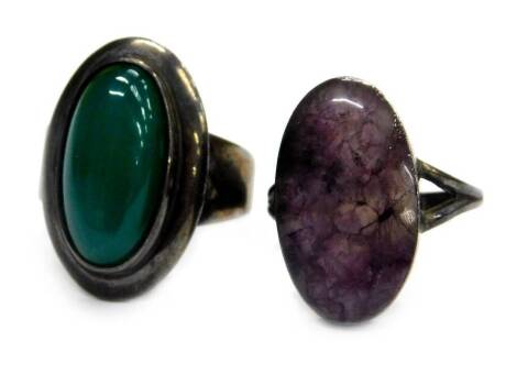 Two stone set dress rings, comprising a green polished stone set dress ring, marked Sterling, Denmark, ring size L, and pale purple stone in silver setting, marked silver, ring size L. (2)